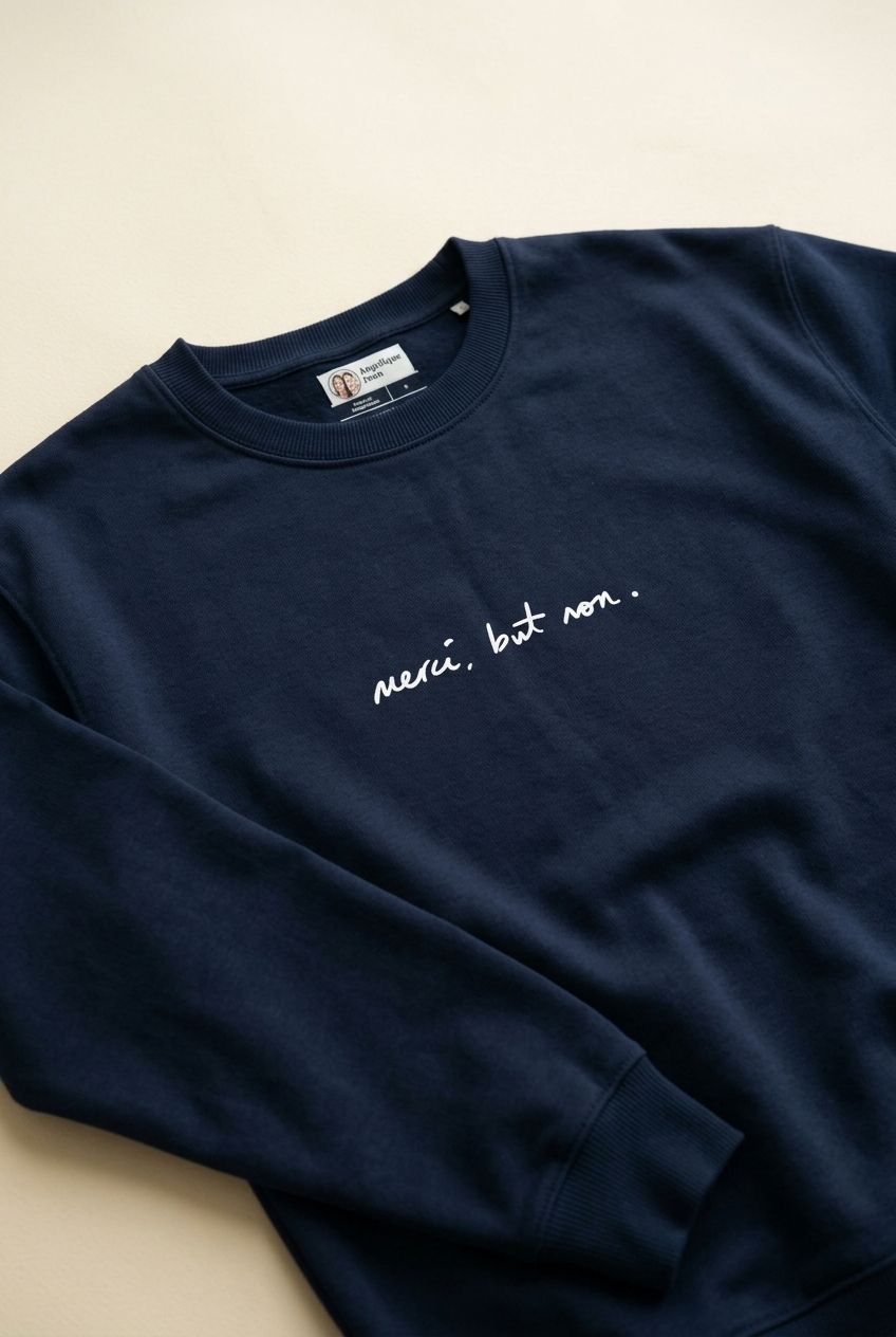 Close-up of navy unisex oversized organic sweatshirt with signature quote, shown on a simple light background with natural indoor lighting.